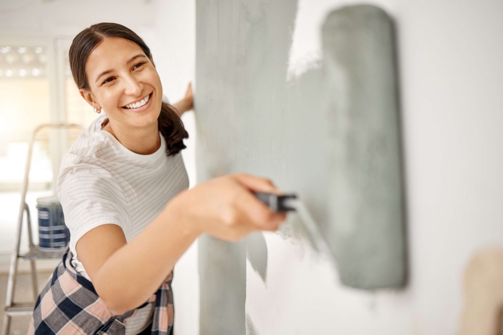 woman happily painting a room with roller brush