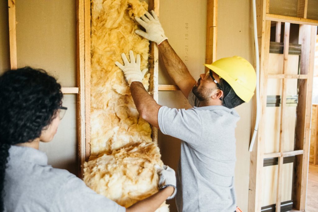 construction workers installing insulation in home framing