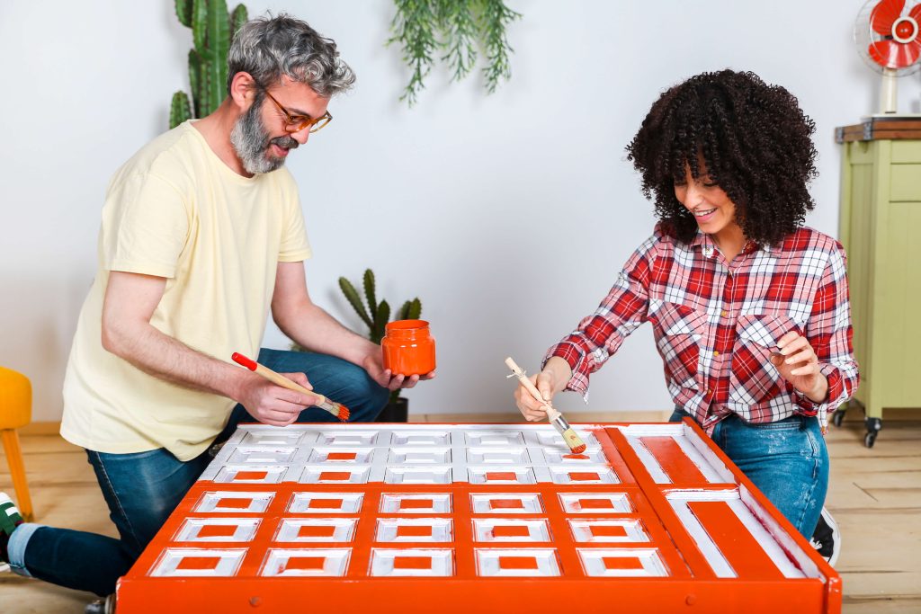 couple painting furniture bright orange