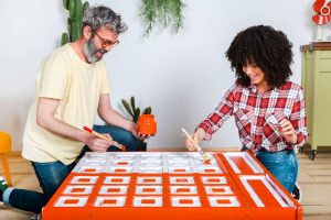 couple painting furniture bright orange