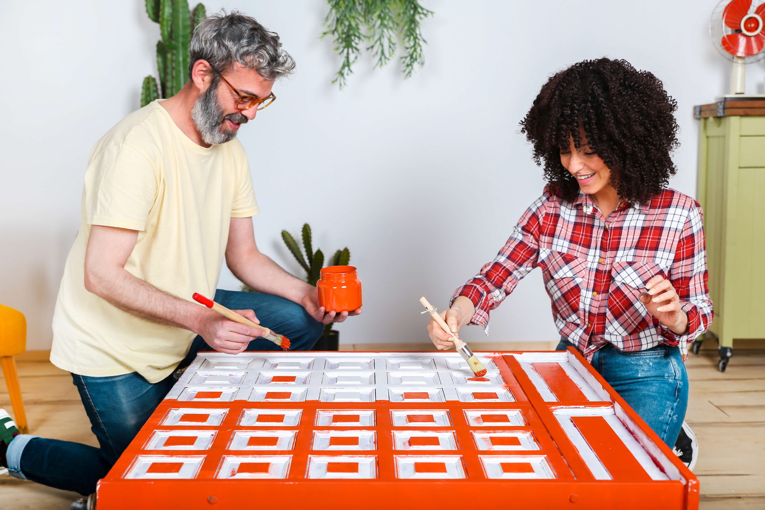 couple painting furniture bright orange
