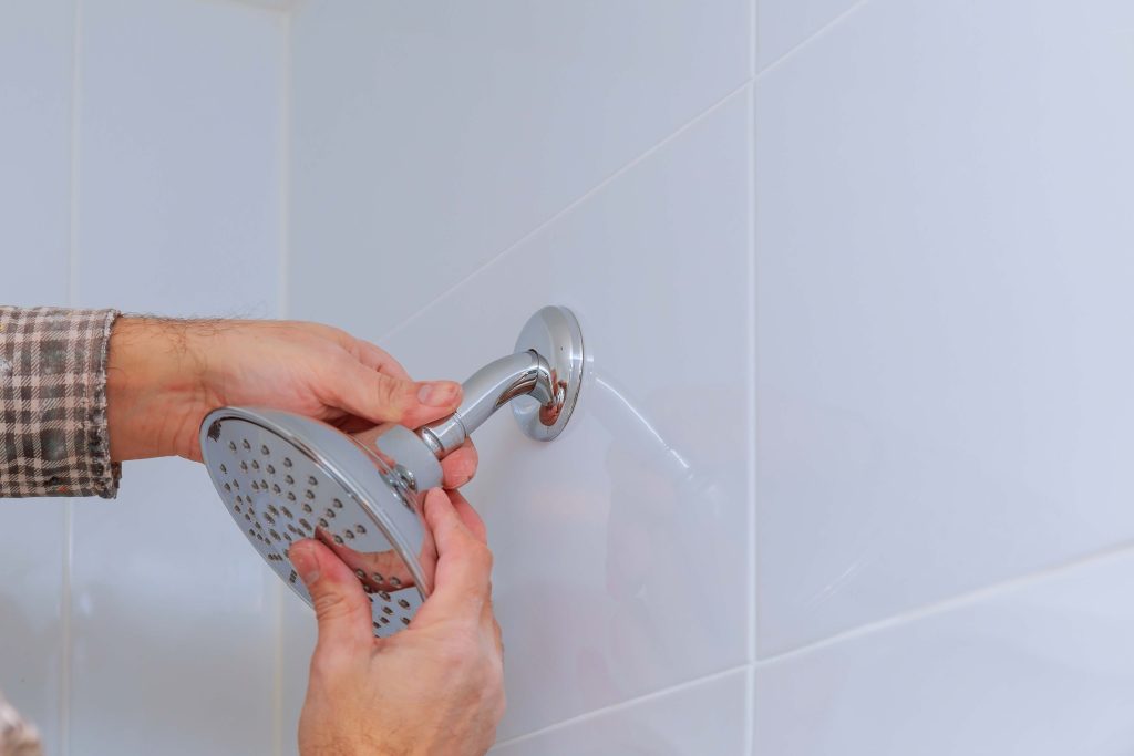 closeup shot of man replacing shower faucet in bathroom