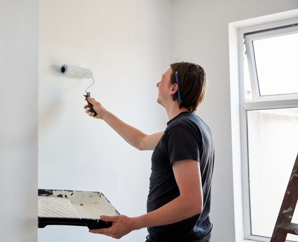 you man in tshirt using primer before painting a room