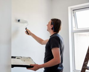 you man in tshirt using primer before painting a room